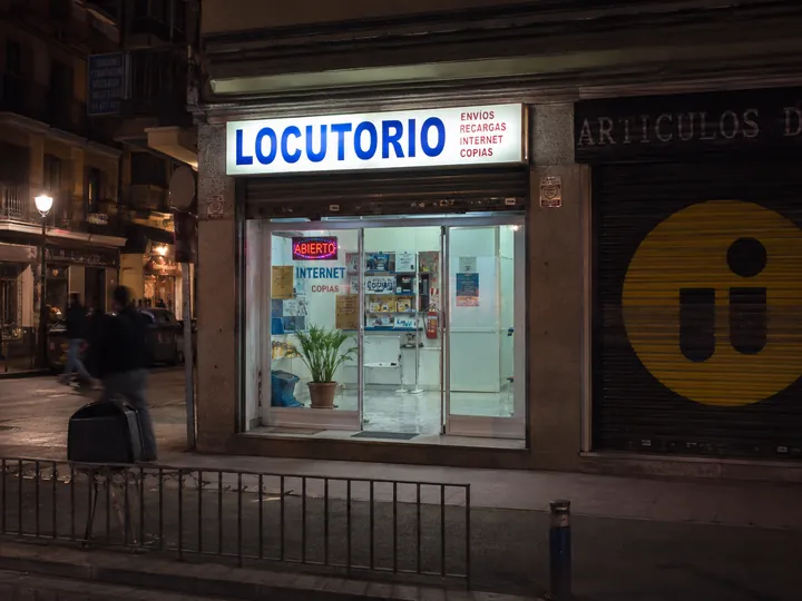 Locutorio en una calle comercial concurrida al anochecer