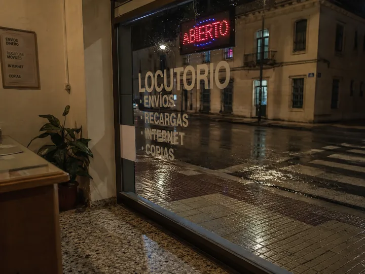 Vista desde dentro del locutorio hacia la calle con lluvia