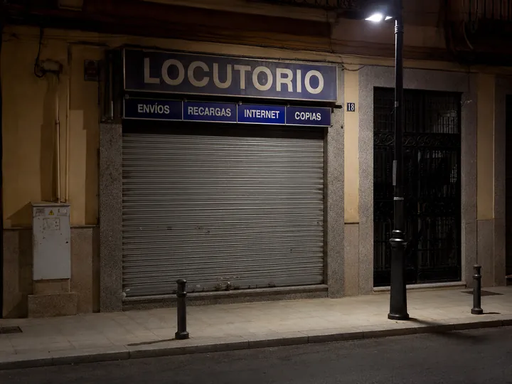 Locutorio cerrado con la persiana bajada, farola encendida